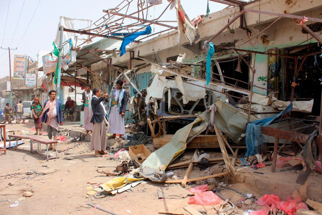 Yemenis gather next to the destroyed bus at the site of a Saudi-led coalition air strike, that targeted the Dahyan market the previous day in the Huthi rebels&amp;#039; stronghold province of Saada on