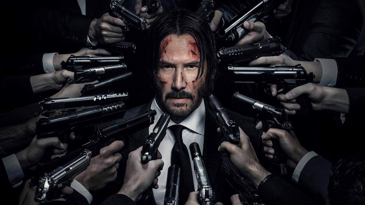 Keanu Reeves as John Wick with guns pointed at him