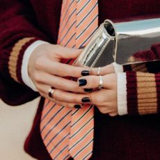 close up of woman at fashion week holding a silver bag with her dark nails on show