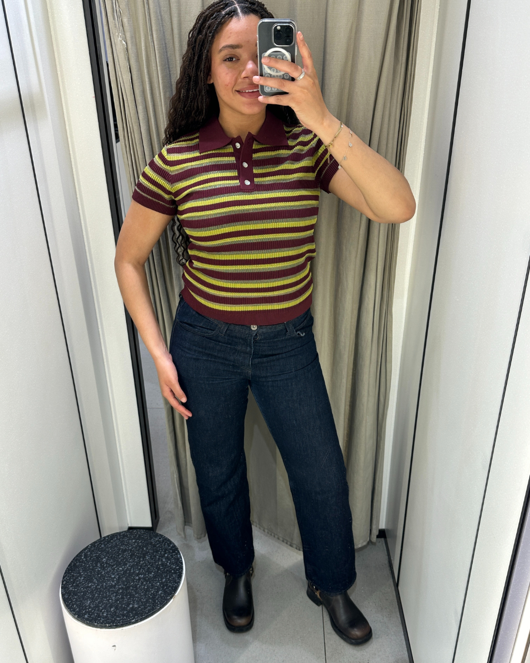 Imani-Nia Francis-Tsolakis in a burgundy, yellow and khaki polo top dark blue jeans and biker boots.