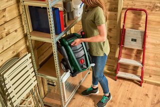 woman storing a Bosch pressure washer in a shed