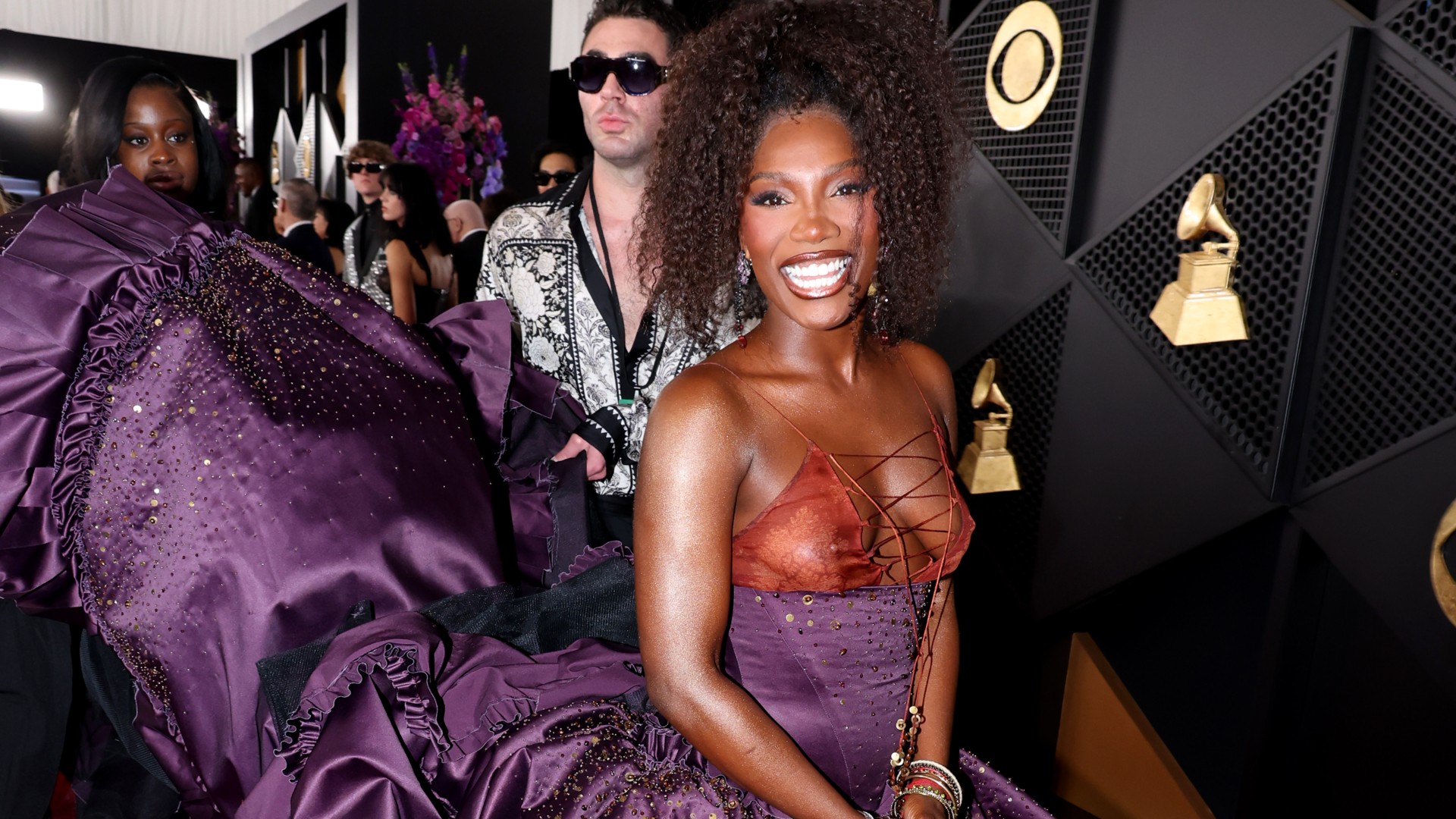 a black woman with brown hair poses on the grammys red carpet