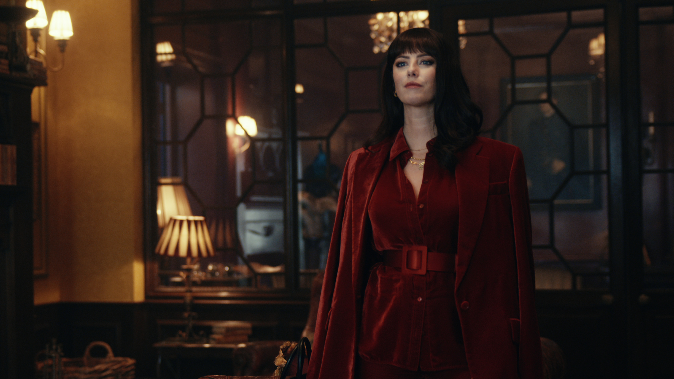 Susie Glass (Kaya Scodelario) in a red dress in a scene from Netflix's "The Gentlemen"