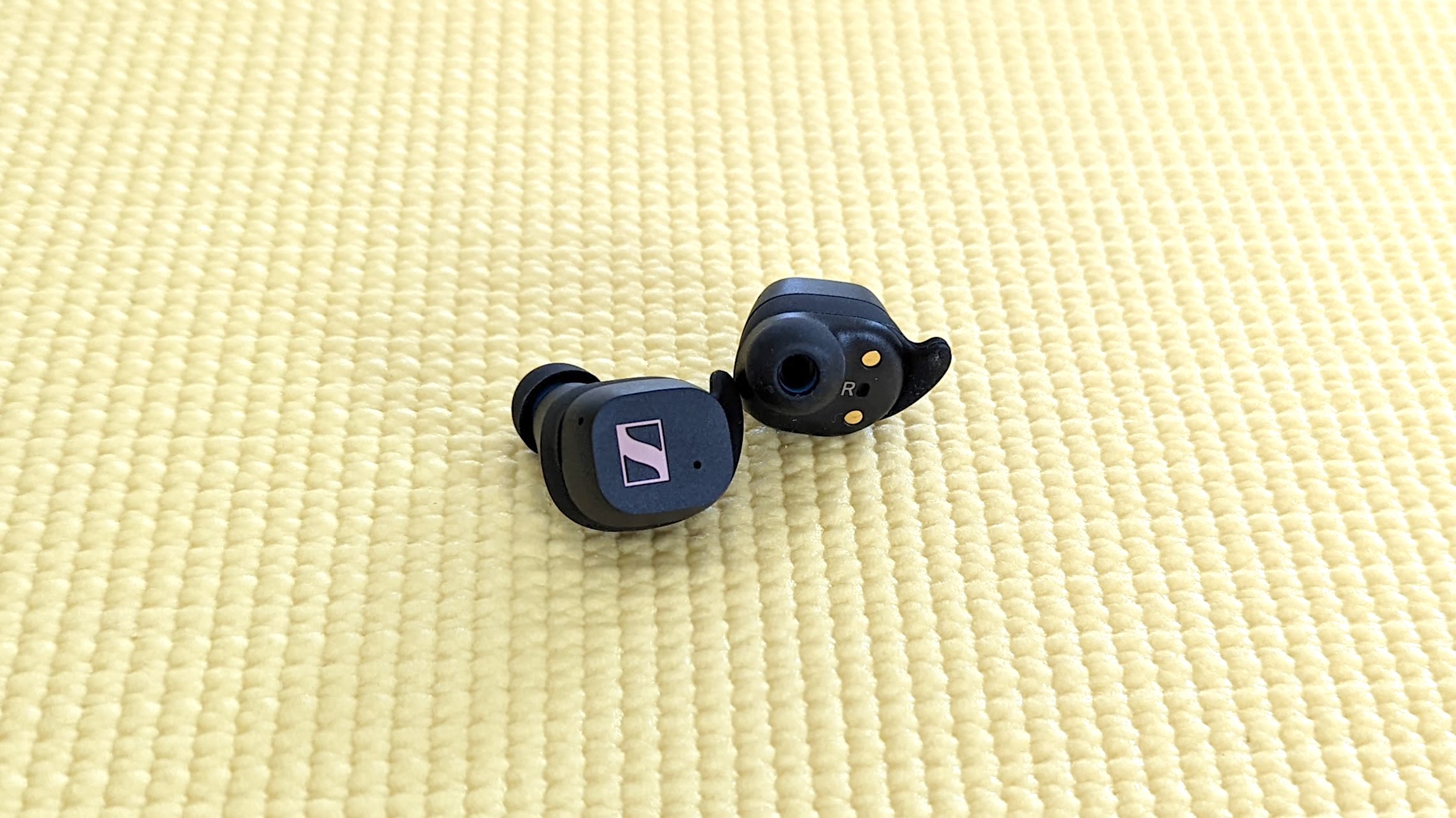 The Sennheiser Sport True Wireless wireless earbuds placed on top of a yoga mat