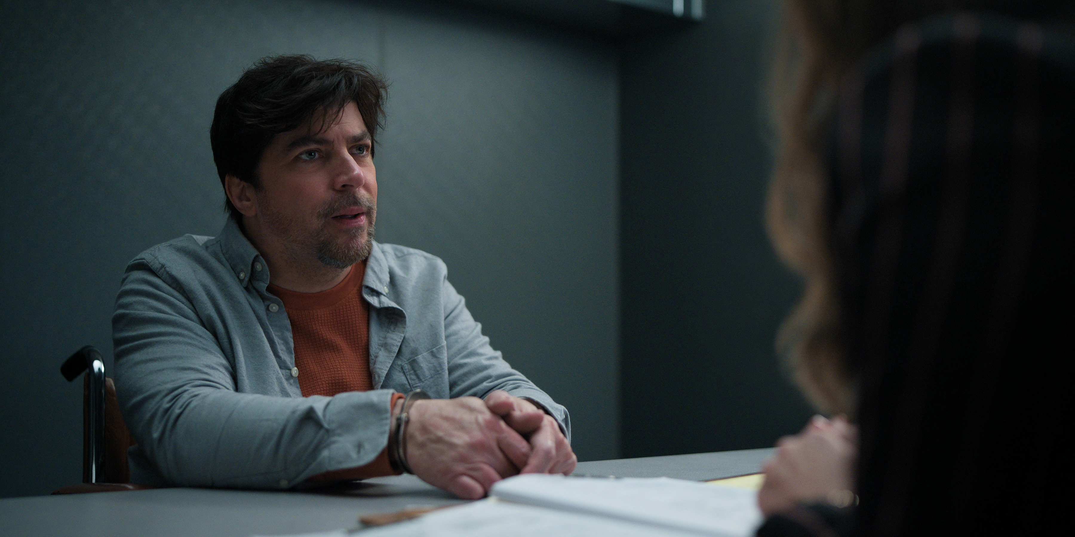 A man in a denim shirt (Christopher Thornton as Sam Scales) sits in a police interrogation room, in episode 307 of 'The Lincoln Lawyer.'