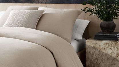 Is it better to sleep without a pillow? Neutral bedding in neutral bedroom with layers of cushions 