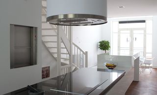A kitchen space featuring white and silver decor. A long island with black marble top and a fruit bowl with banana