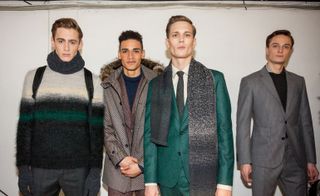 Four models stood next to each other looking into the camera wearing suits and jumpers