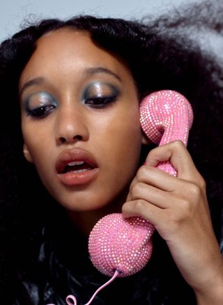 Girl wearing glossy blue eyes and holding pink glittery phone
