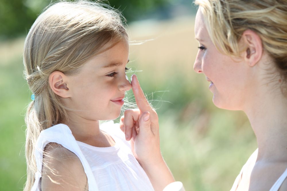 A mom taps her daughter on the nose.