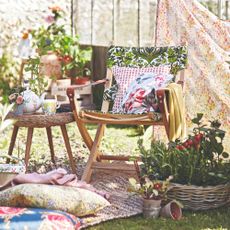 A garden with a chair and blanket and tomato plants