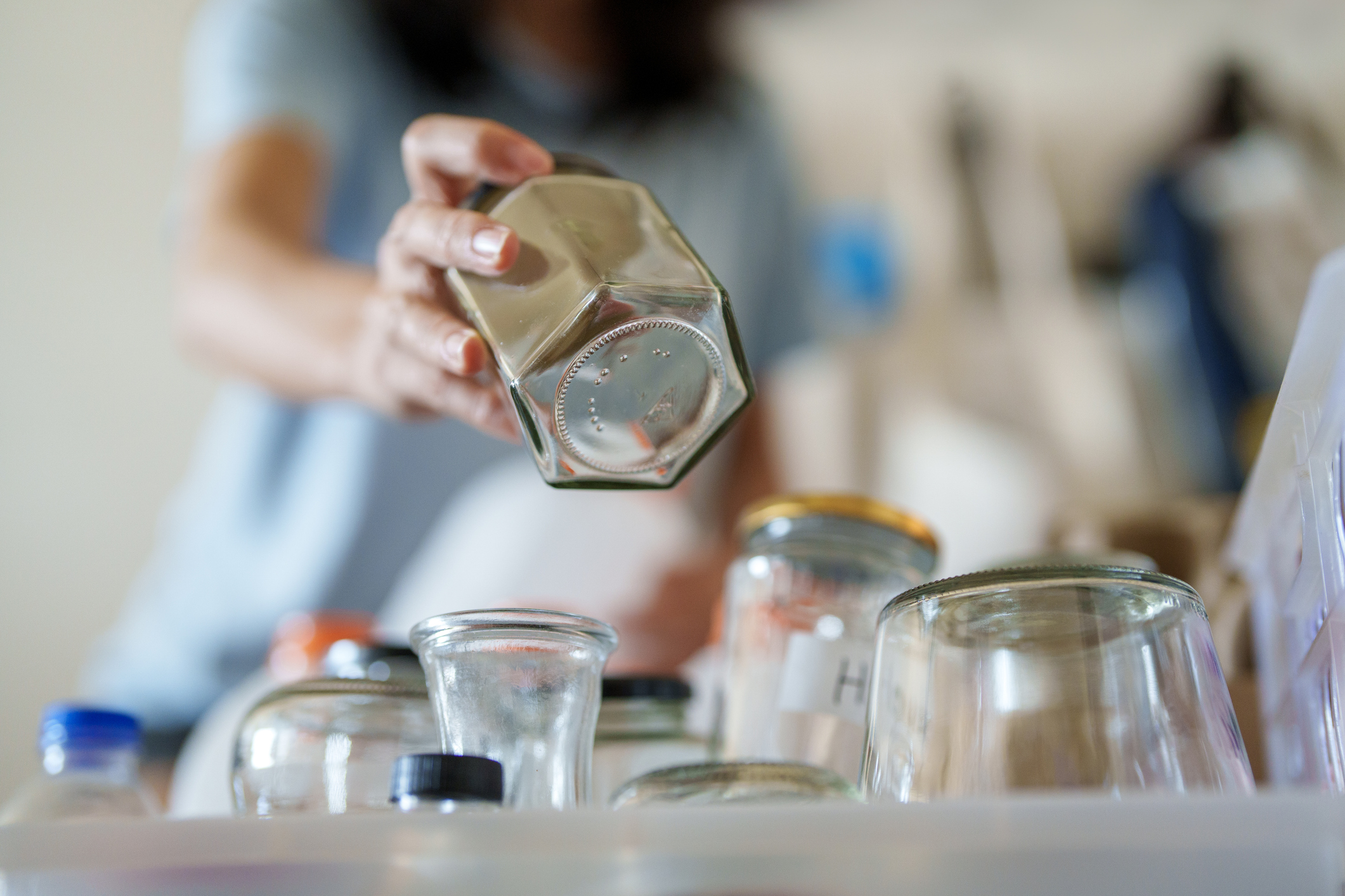 A woman adds an empty jar to a pile of empty jars in her kitchen.
