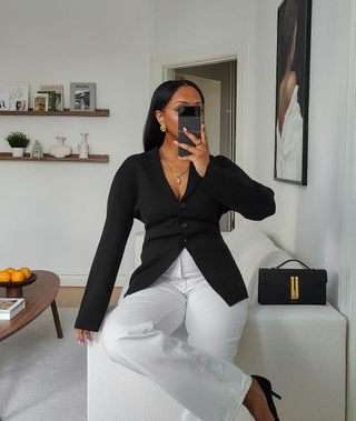 @femmeblk wearing a black cardigan with white trousers