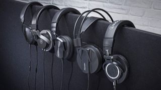 A row of headphones against a white brick wall