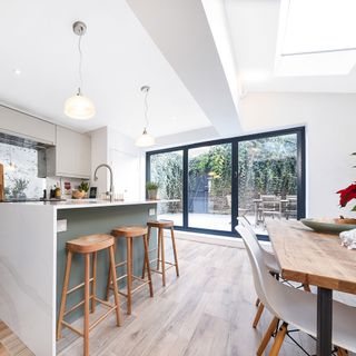 side return kitchen extension with sliding doors and large kitchen island with sink and wooden bar stools