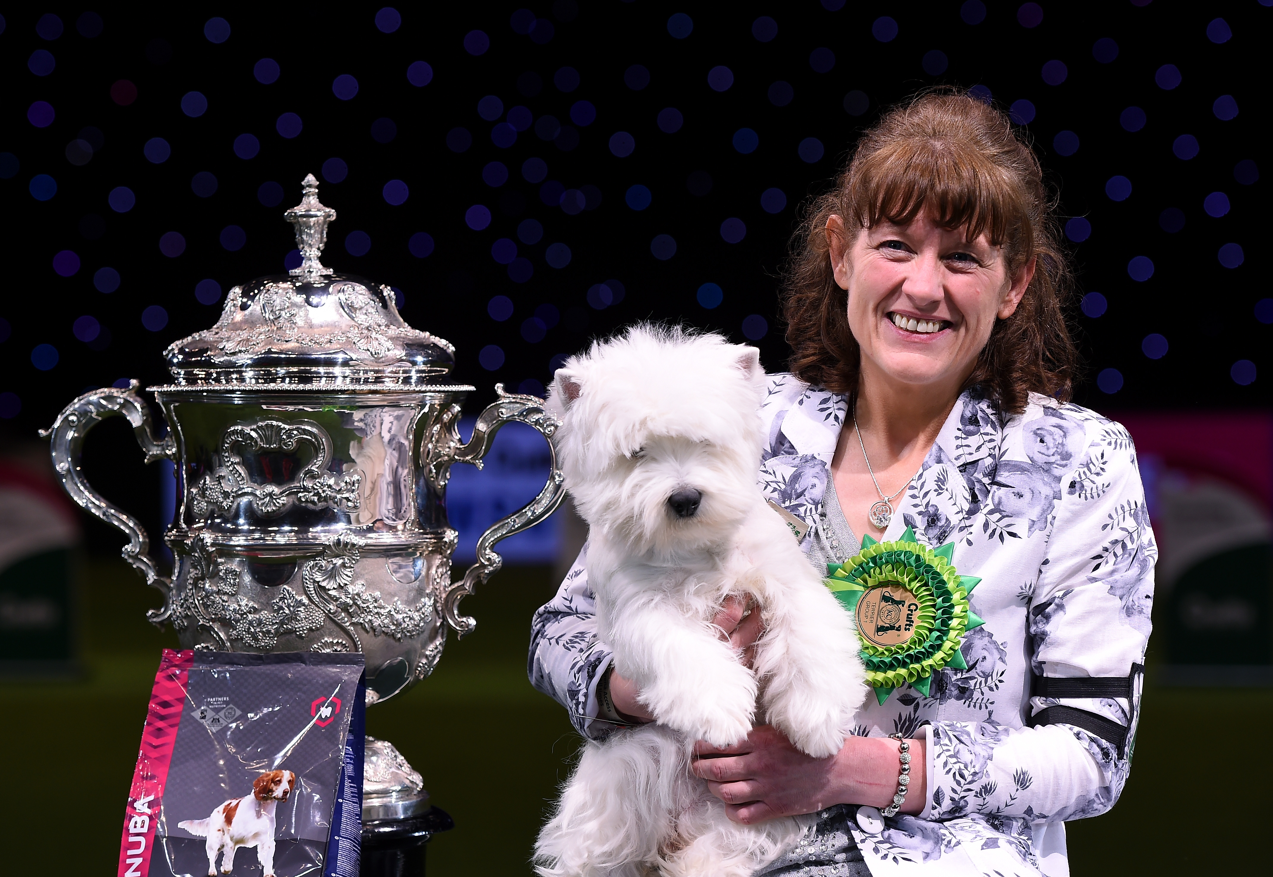 West Highland white terrier Burneze Geordie Girl with handler Mrs Marie Burns and the Crufts Best in Show trophy at the NEC in Birmingham, 2016.