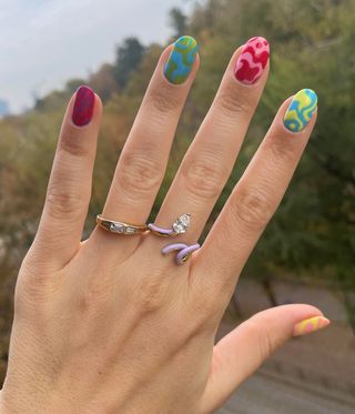 Woman's hand with brightly coloured nails and rings