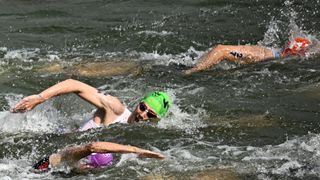 A group of swimmers swims through the Seine during the men's triathalon at the Paris Games