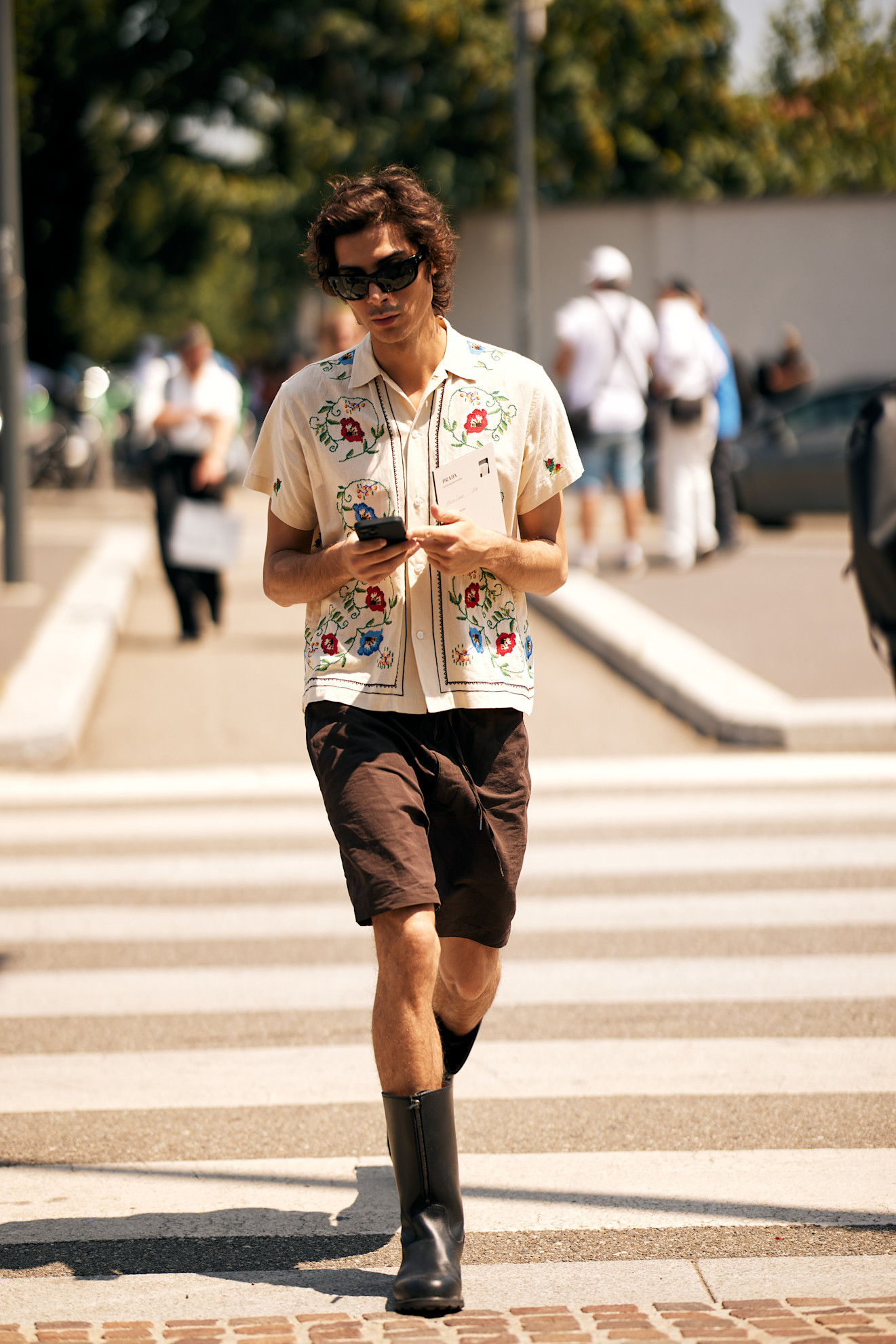 Mens Fashion Week SS26 showgoer wearing a blue shirt tucked into a brown textured miniskirt with brown rope sandals and a black tote bag.