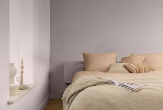 A bedroom with pale pink walls and terracotta bedding