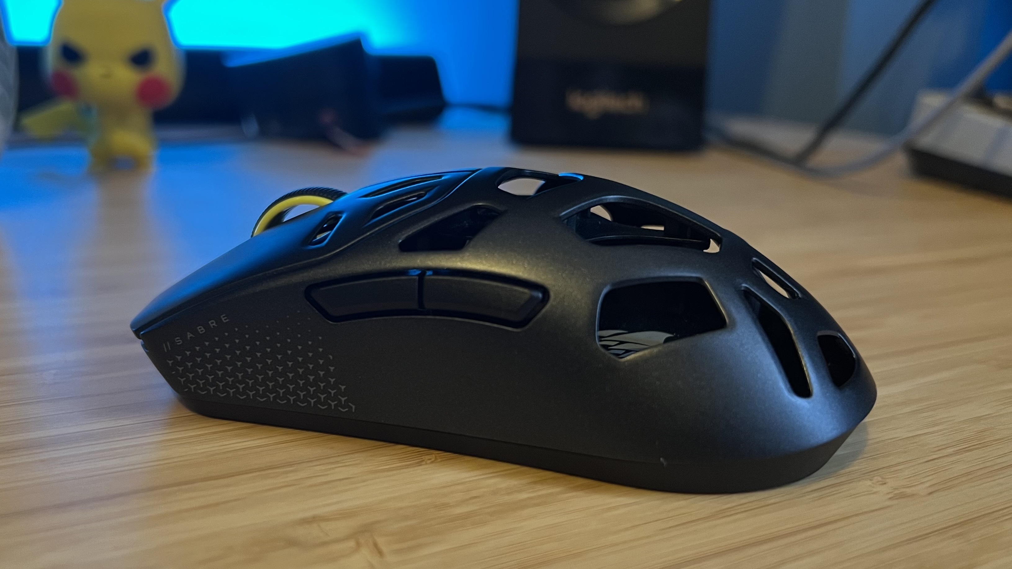 Left flank of the Corsair Sabre V2 Pro Wireless MG gaming mouse showing side buttons on a wooden desk