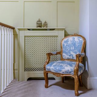 A landing with an antique chair and a radiator cover