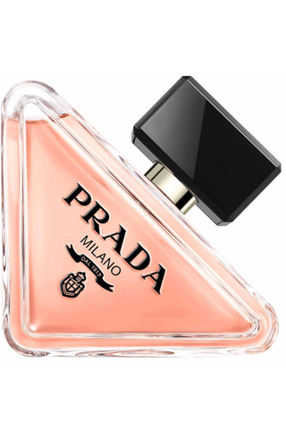 A bottle of Prada Beauty perfume on a plain backdrop