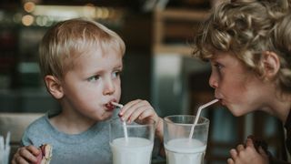 Two boys drinking a glass of milk