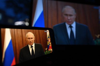 A photo of Vladimir Putin addressing the public on a screen