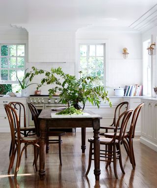 white kitchen with large rustic wooden dining table in center acting as a kitchen island