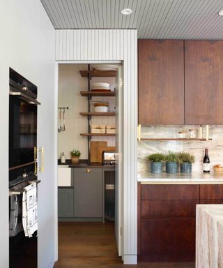 A utility room with open shelving connected to a kitchen