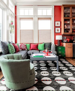 family room with red walls, gray sofa, green armchair and black and white rug