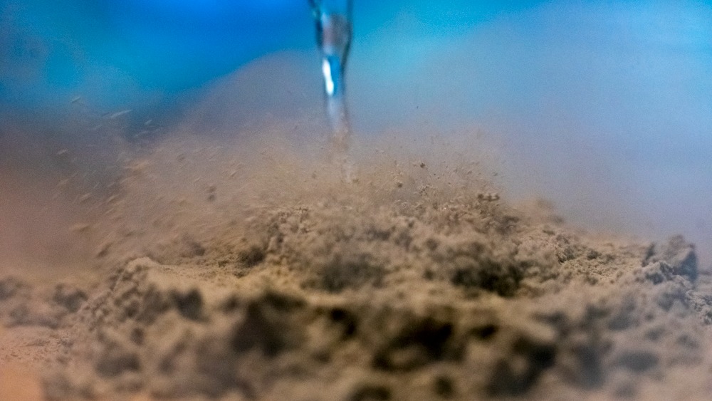Una imagen de primer plano de un cuentagotas que libera nitrógeno líquido sobre una pila de ceniza volcánica.