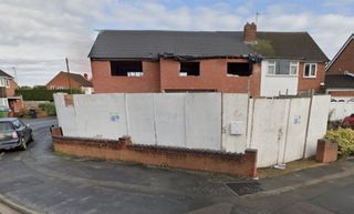 The front of a self build with screens in front. The home is empty and is just the brick walls and roof