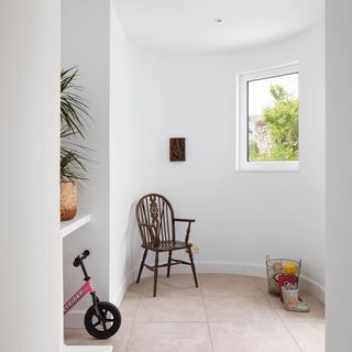 hallway with white wall and wooden chair