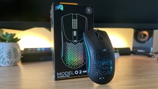 Glorious Model O 2 Mini Wireless gaming mouse leaning against its packaging on a wooden gaming desk