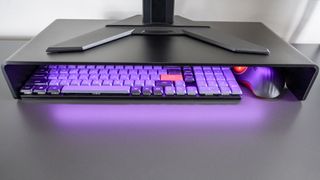 A keyboard and trackball mouse stowed underneath the Razer Monitor Stand Chroma