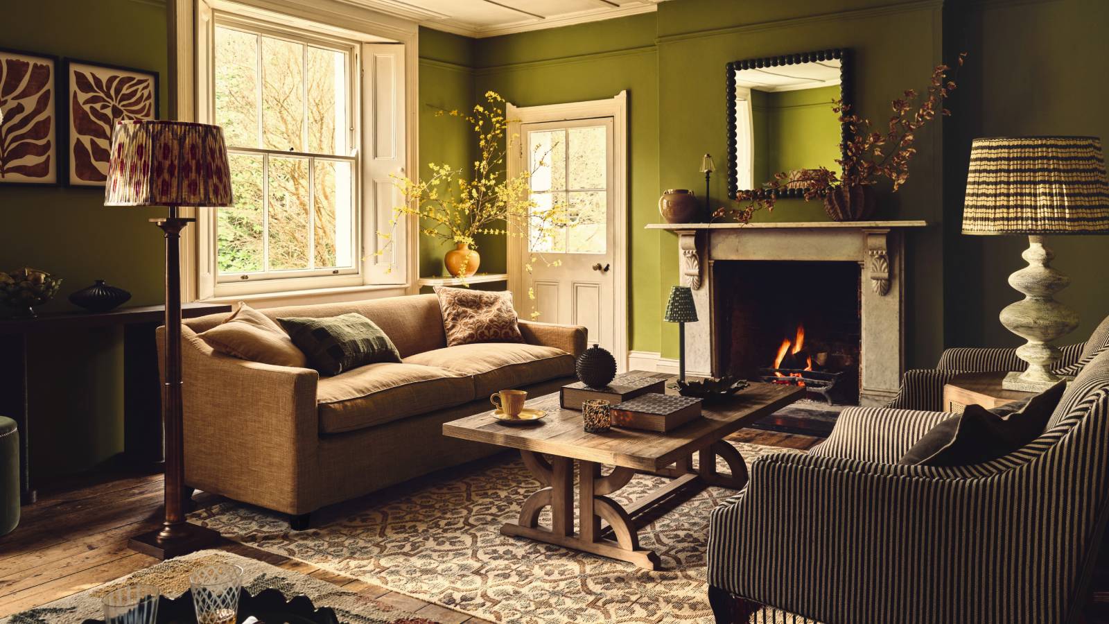 green living room with patterned rug and lit fireplace