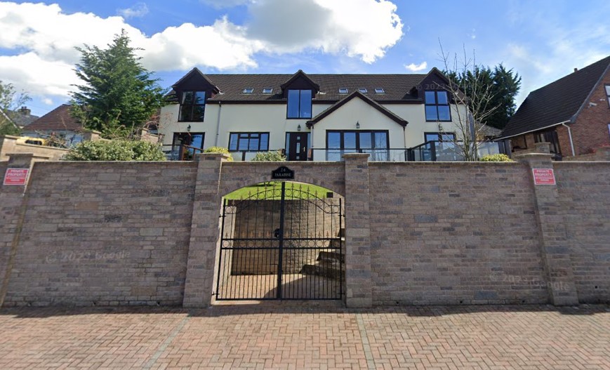 The front retaining wall of the property's gates with a sign saying "Paradise" on it