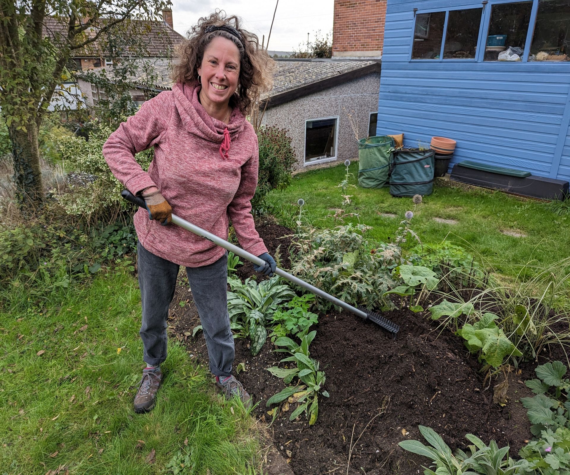 Woman mulching a yard border in the fall using homemade compost