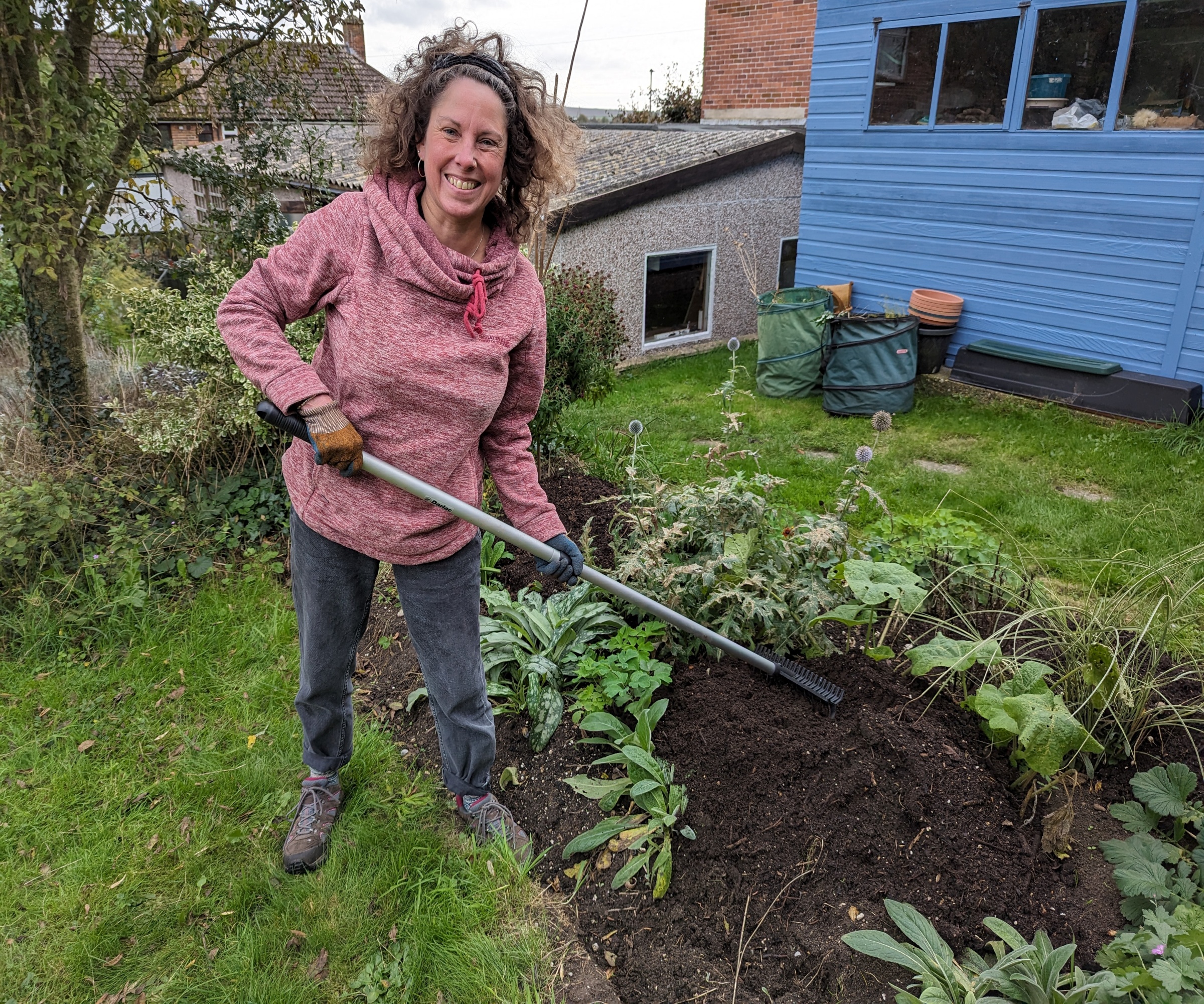 Woman mulching a yard border in the fall using homemade compost