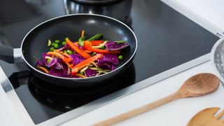 A pan filled with peppers and vegetables cooking on an induction cooktop