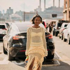 Woman wears crochet top and skirt set with heels and colorful clutch while posing in the NYC streets.