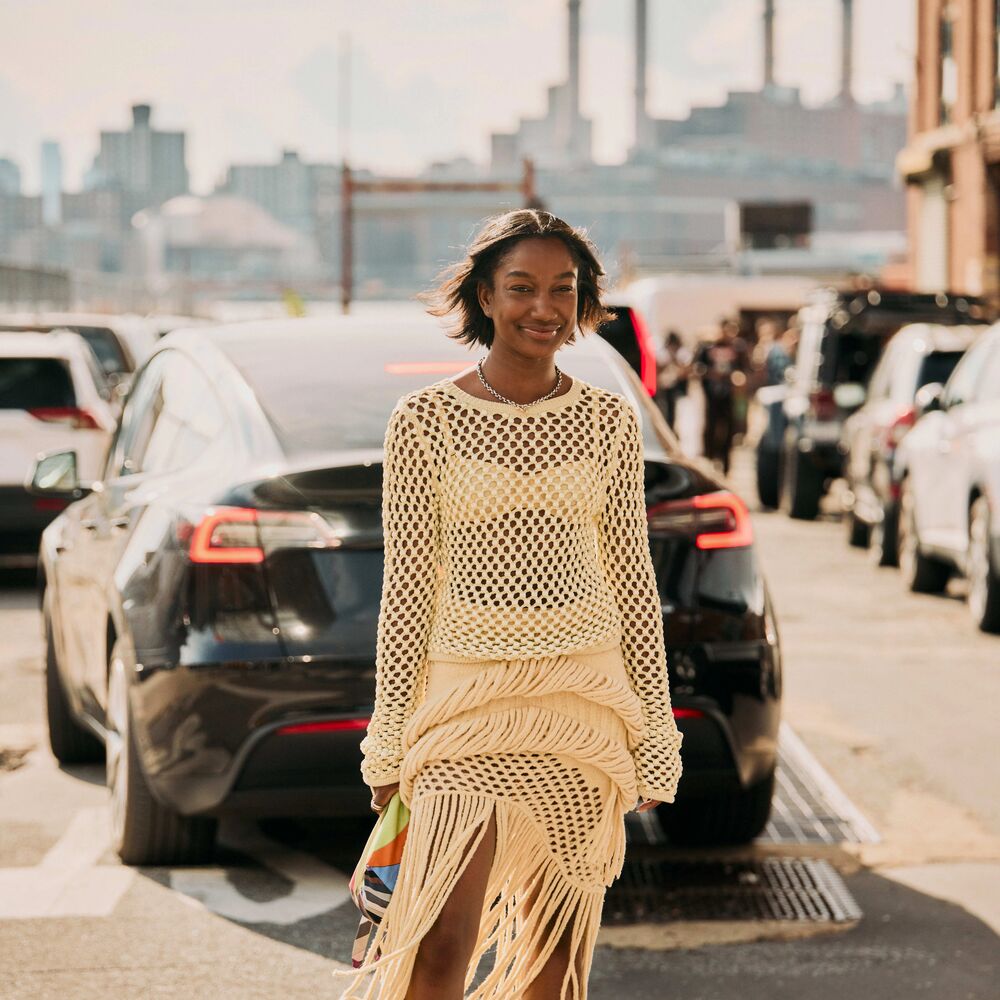 Woman wears crochet top and skirt set with heels and colorful clutch while posing in the NYC streets.