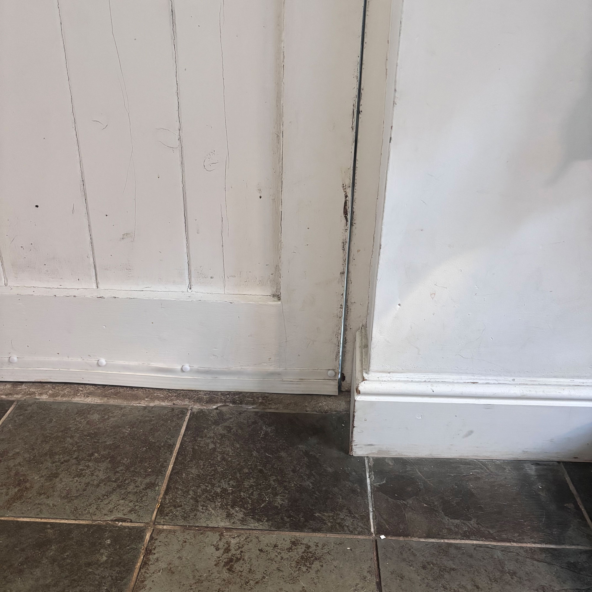 draughty old front door in hallway with slate floor