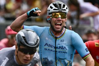 Astana Qazaqstan Team's British rider Mark Cavendish (C) cycles past the finish line ahead of second-placed Alpecin-Deceuninck team's Belgian rider Jasper Philipsen (L) to win the 5th stage of the 111th edition of the Tour de France cycling race, 177,5 km between Saint-Jean-de-Maurienne and Saint-Vulbas, his 35th Tour de France stage victory beating the previous record held by Belgian rider Eddy Merckx, on July 3, 2024. (Photo by Marco BERTORELLO / AFP)
