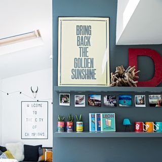 white and blue wall with wall shelf frame on shelf and photos on wall