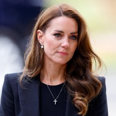 Kate Middleton wears a black blazer and black top and has wavy hair