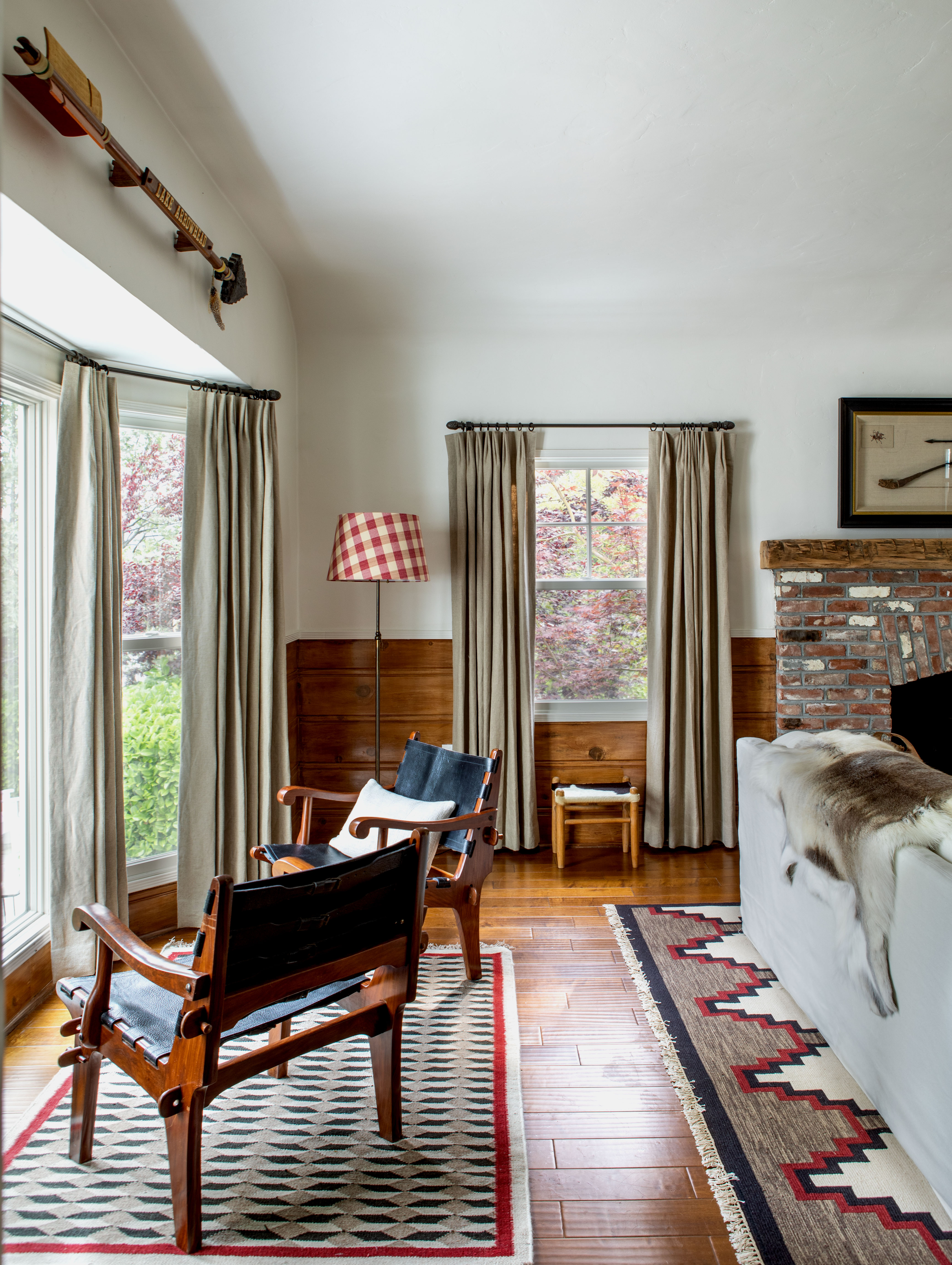A living area with two accent chairs and two patterned area rugs with red accents