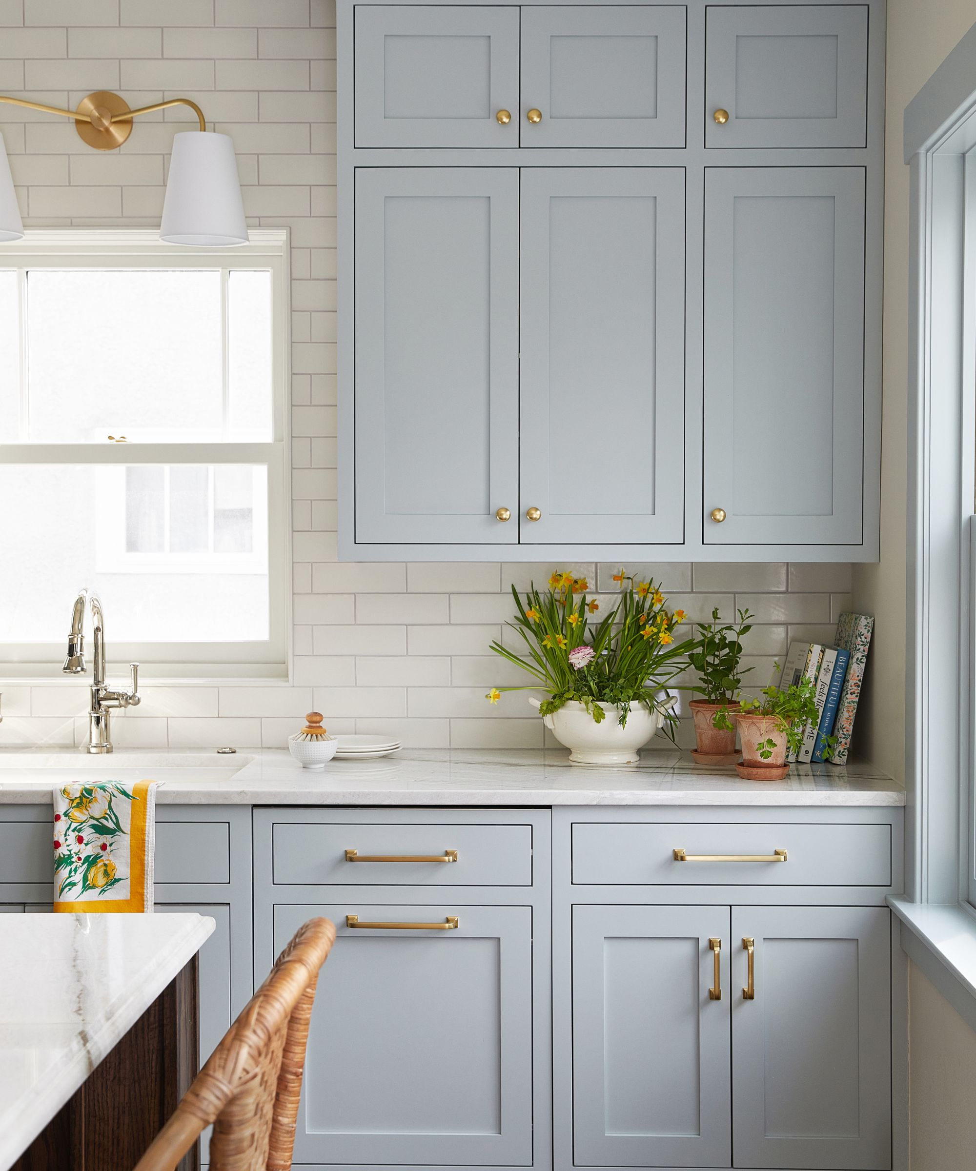 A kitchen with powder blue cabinets, white countertops, and white subway tiles on the wall.